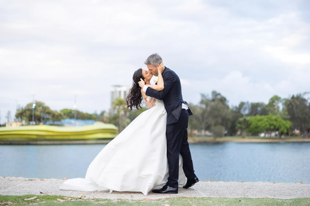 Bride and groom kissing in front of lake