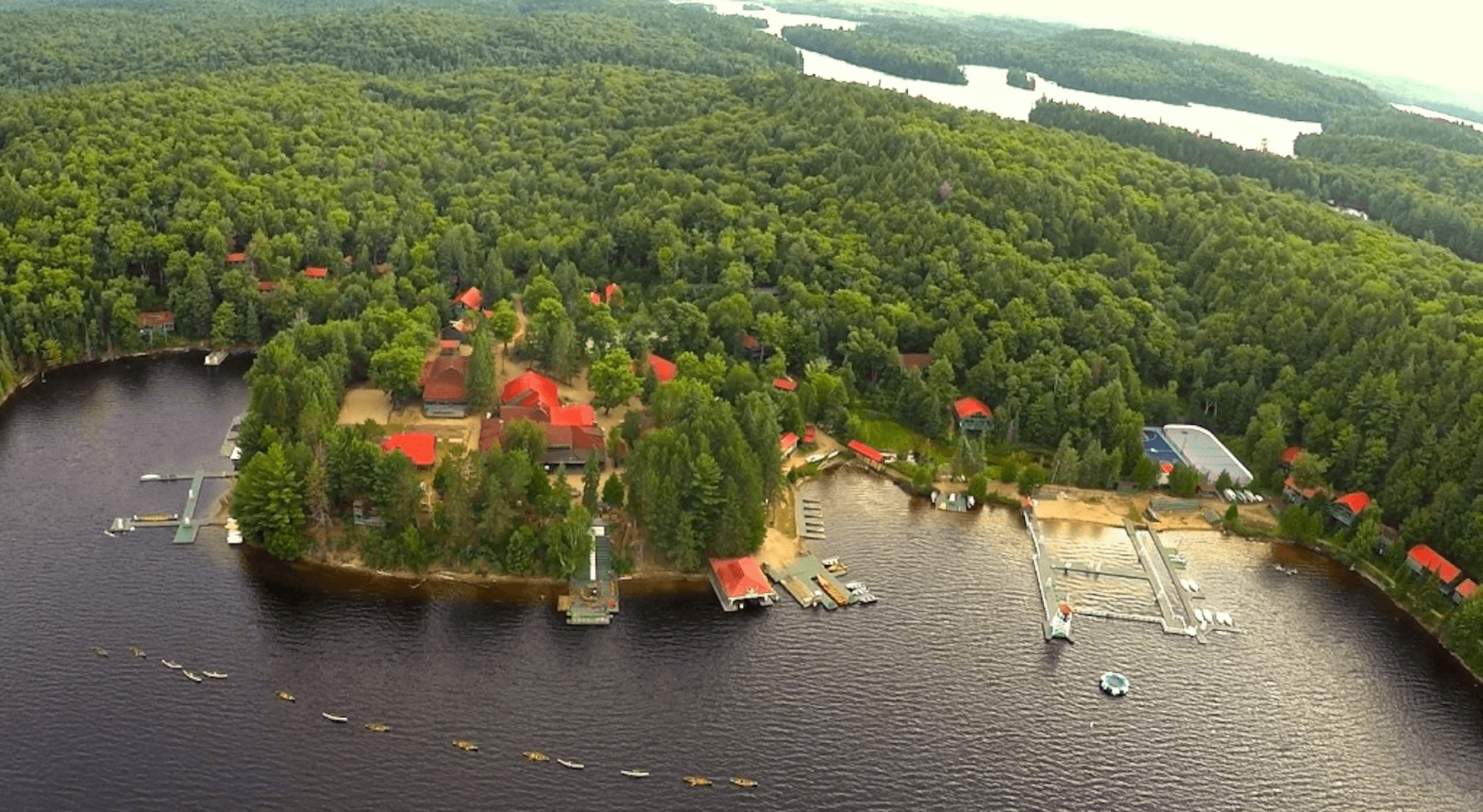 Aerial view of Tamakwa camp on a forested lakeshore in Algonquin Provincial Park.