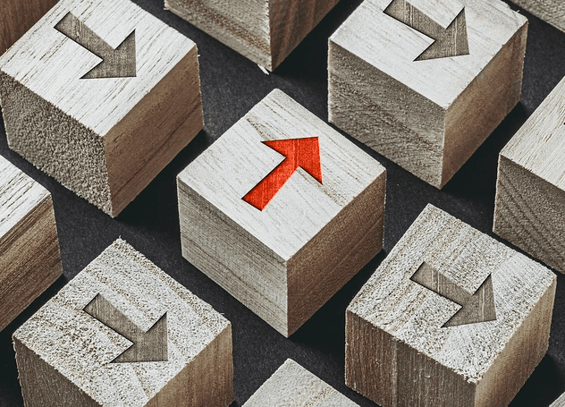 Blocos de madeira com setas apontando para baixo enquanto uma seta laranja aponta para cima