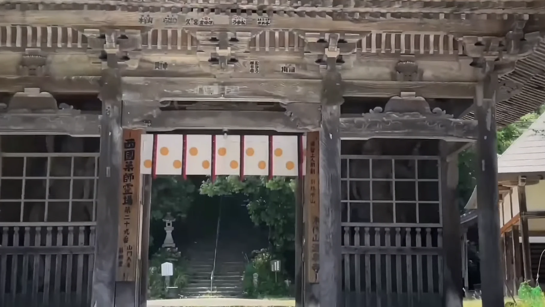 The timber gate of Onsenji temple above Kinosaki framed by summer greenery.