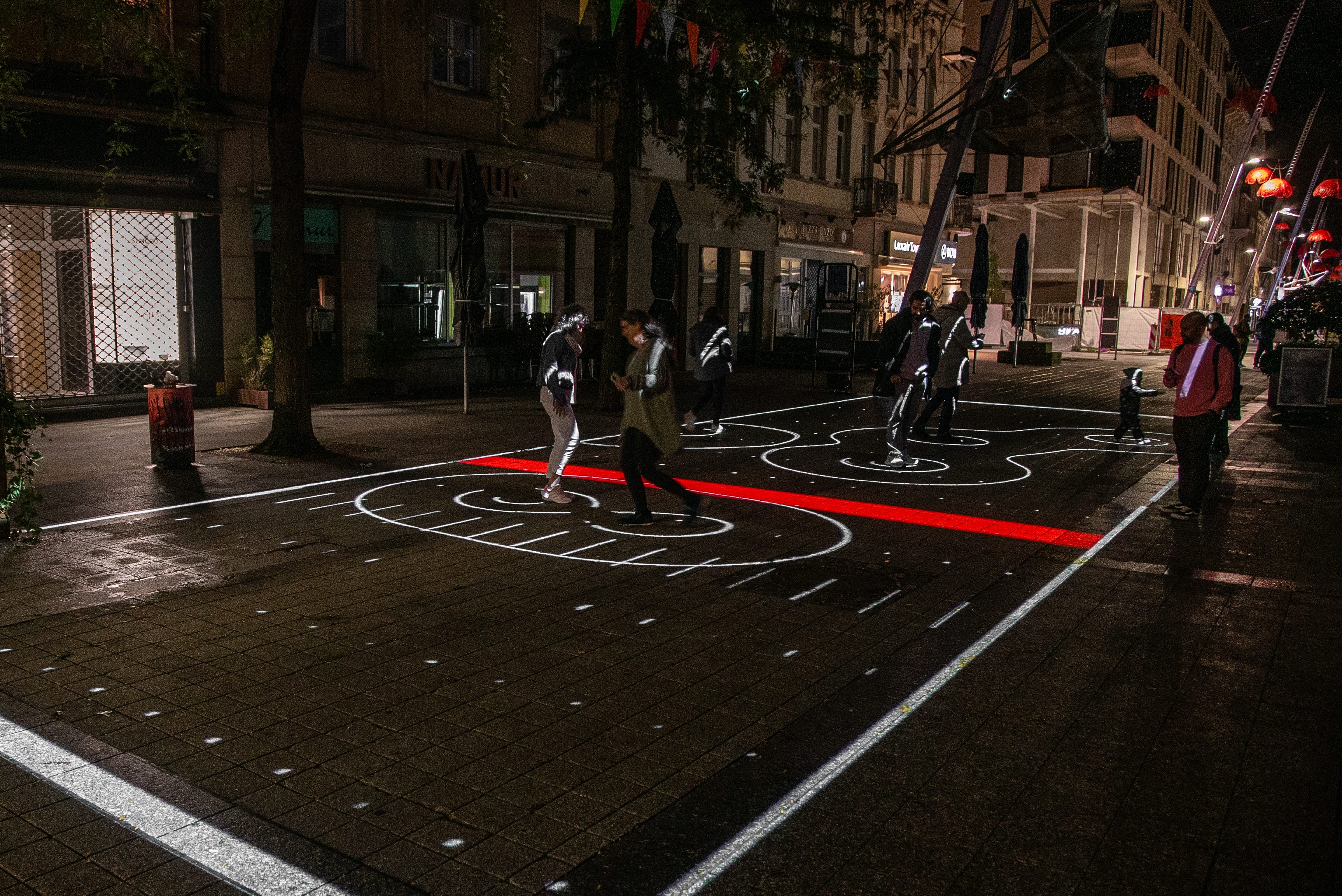 Street scene with red glowing geometric light patterns, pedestrians walking nearby