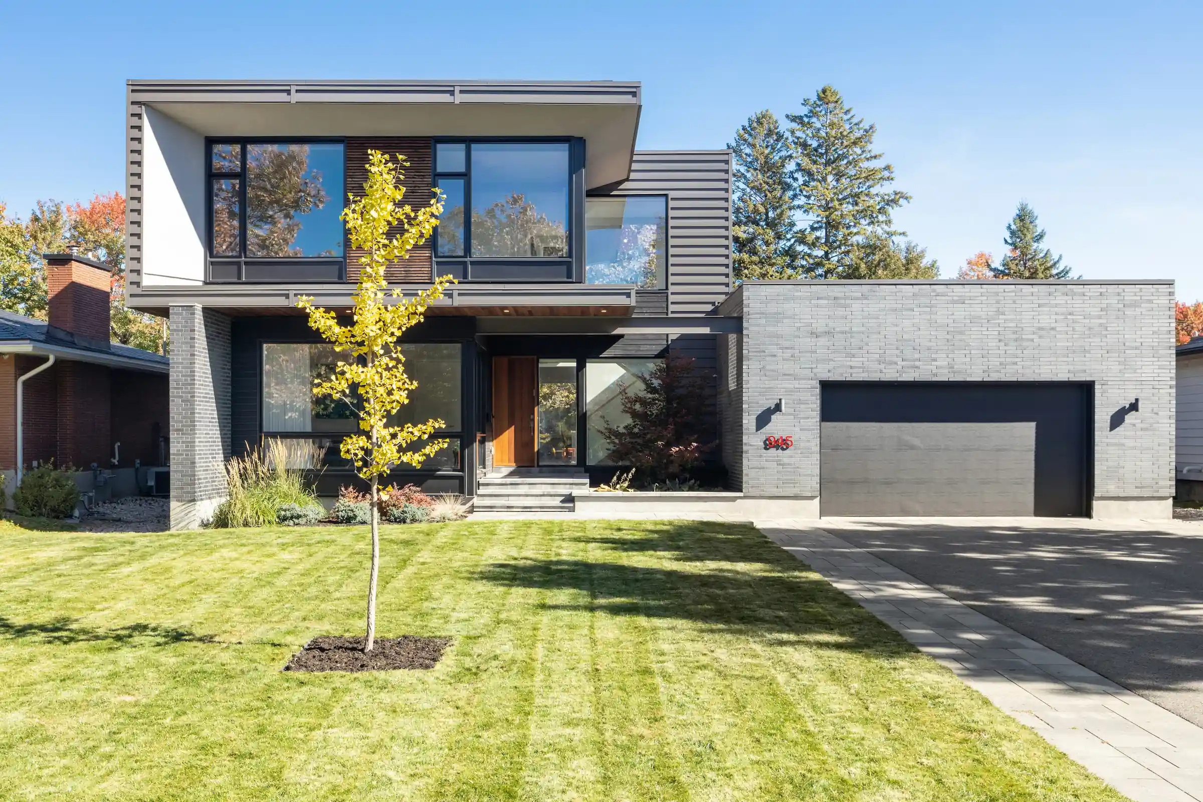 Modern timber-clad residence with horizontal wood facade and geometric volumes set on manicured lawn