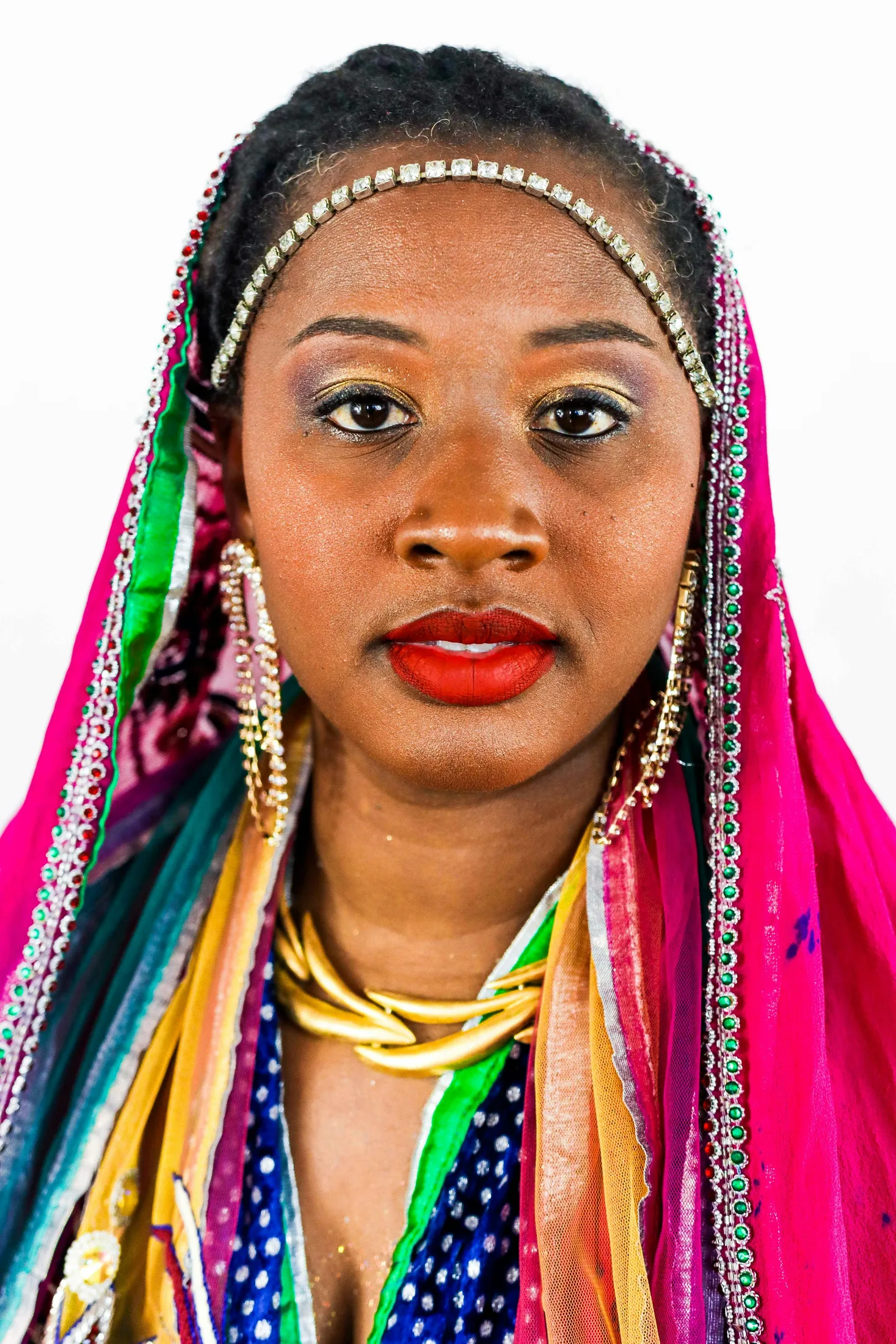 A woman in a bright beaded headscarf looking into the camera