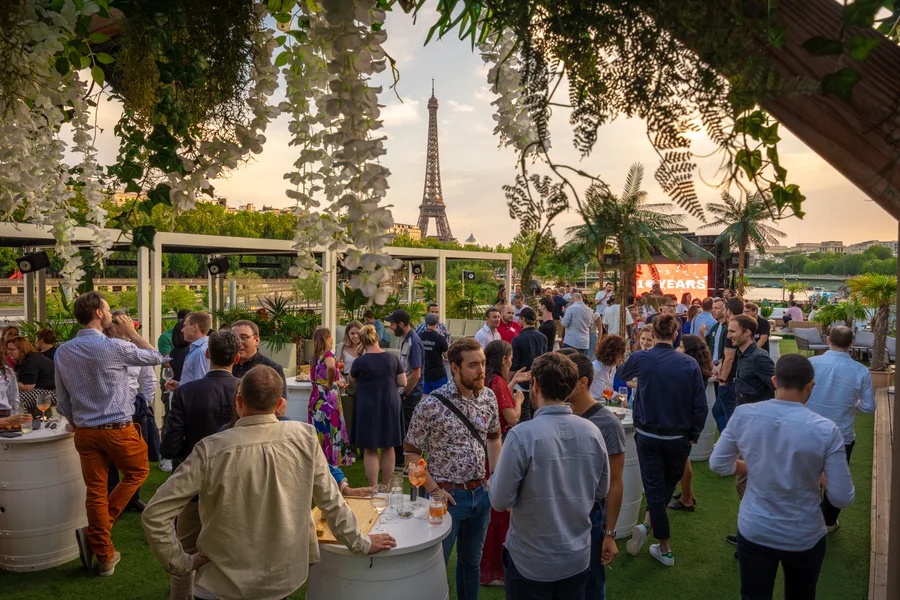 Participants à la soirée des 10 ans de Malt sur une péniche à Paris, avec la tour Eiffel en arrière-plan.