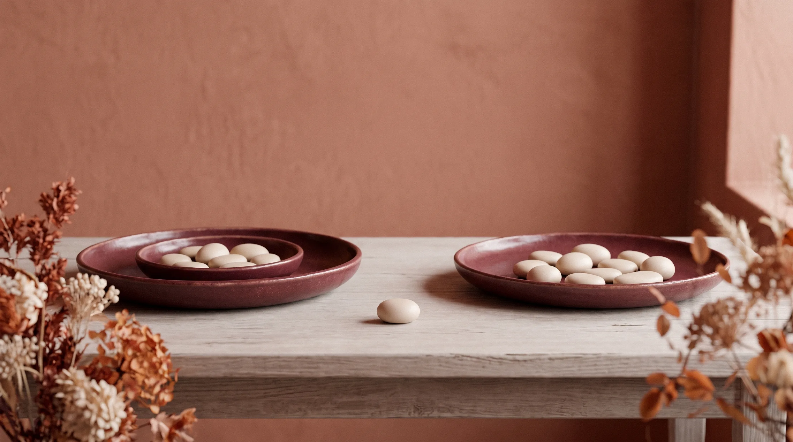 Two dishes holding matching objects, with one object sitting alone between them