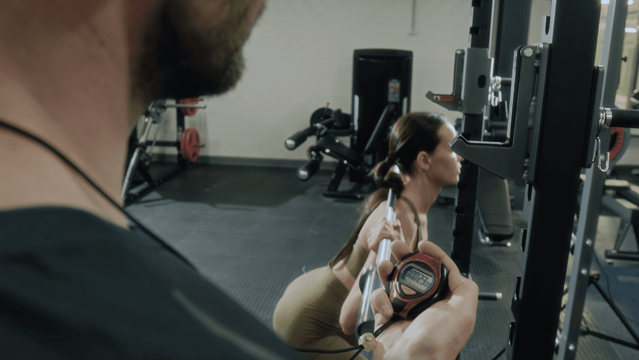 A personal trainer times a woman performing a squat