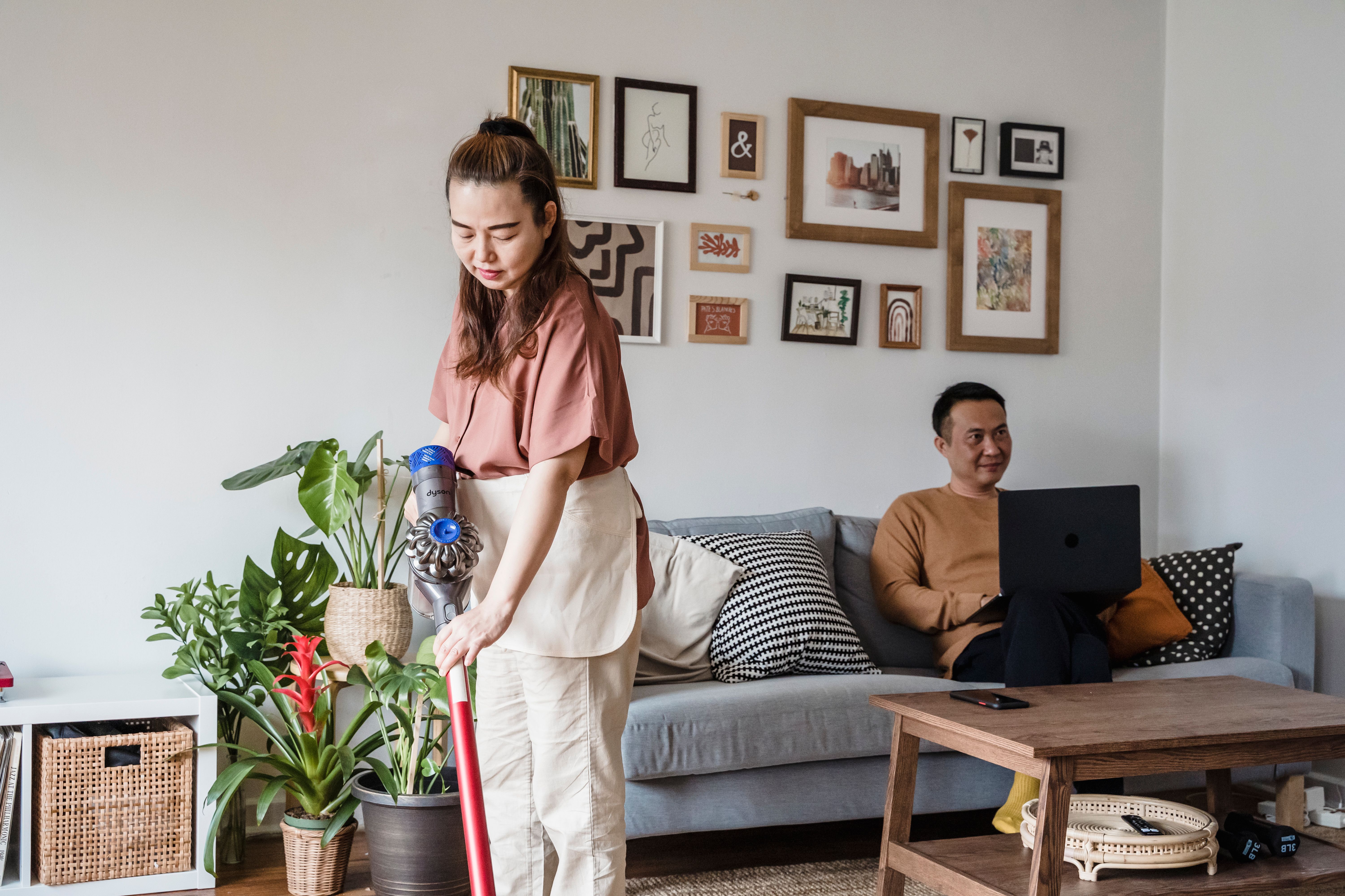 A couple sharing household chores in their kitchen, using a shared chore app on a phone.