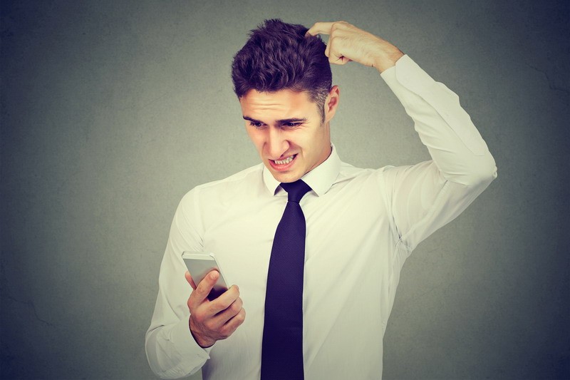 Clueless confused business man having troubles with his smartphone. Complicated technology concept