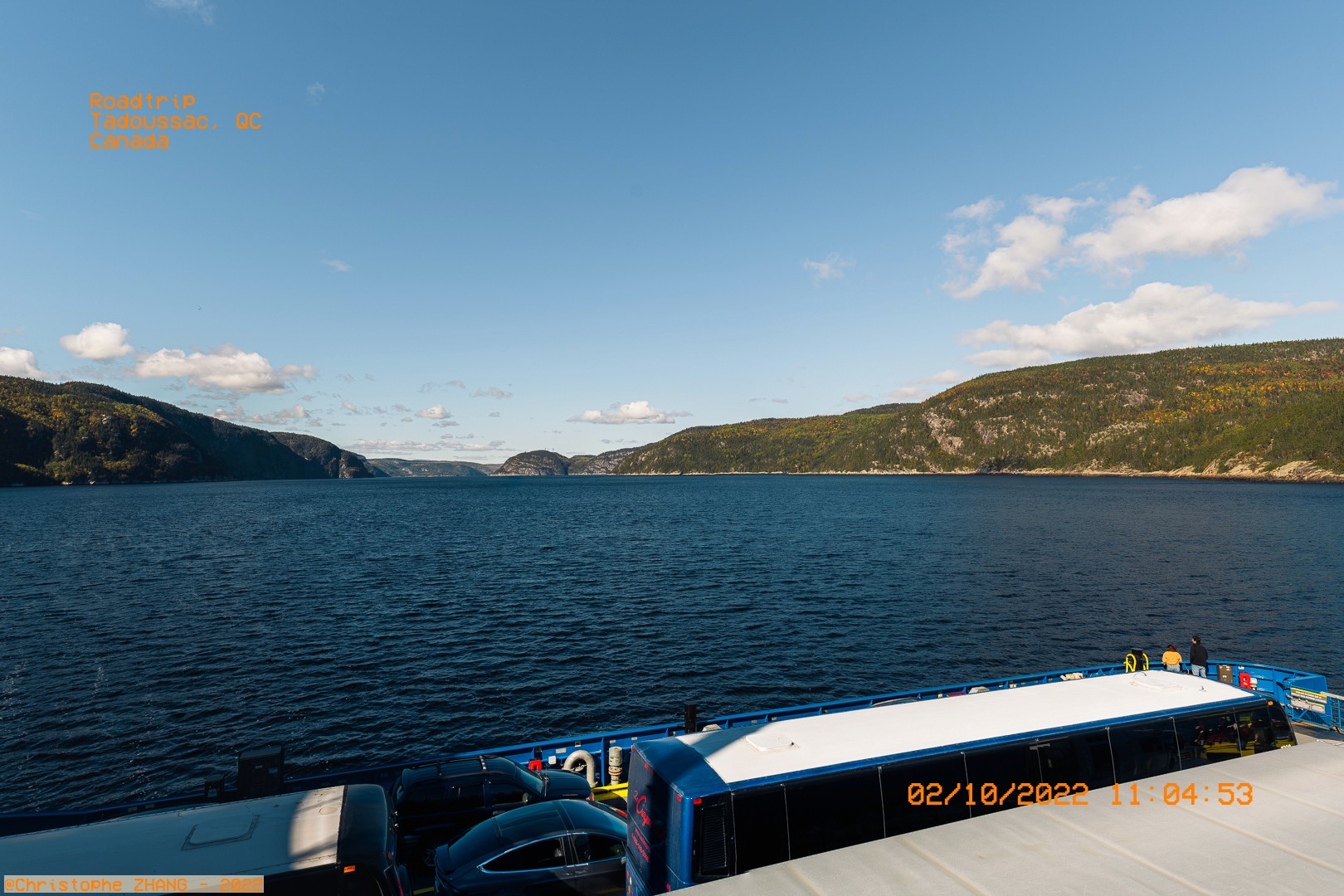 Vue panoramique du fjord du Saguenay depuis un ferry, sous un ciel bleu dégagé.