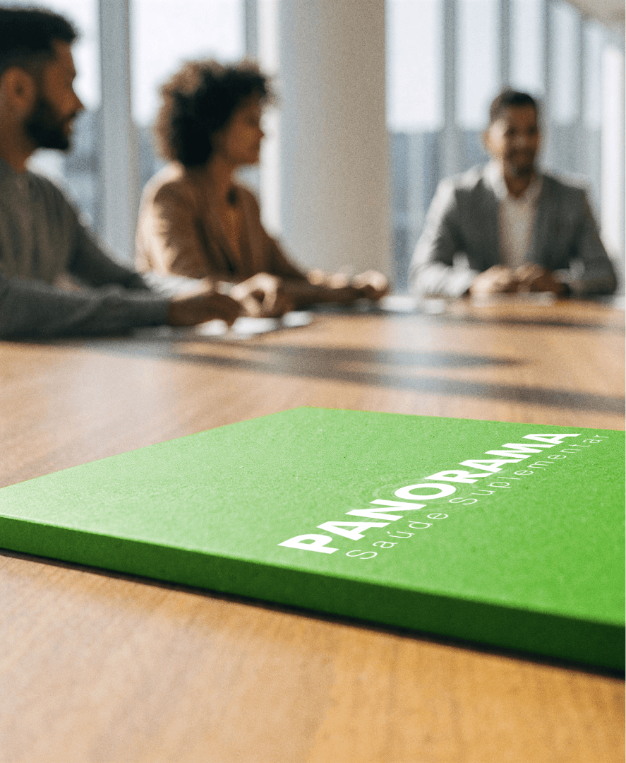 Folheto verde sobre uma mesa de reunião, com pessoas desfocadas ao fundo discutindo dados sobre gestão de clínicas com a Tivita.