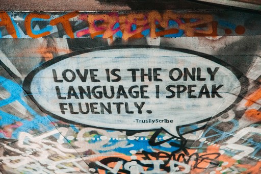 a wall with inscruption "love is the only language i speak fluently", illustrating the english speaking person