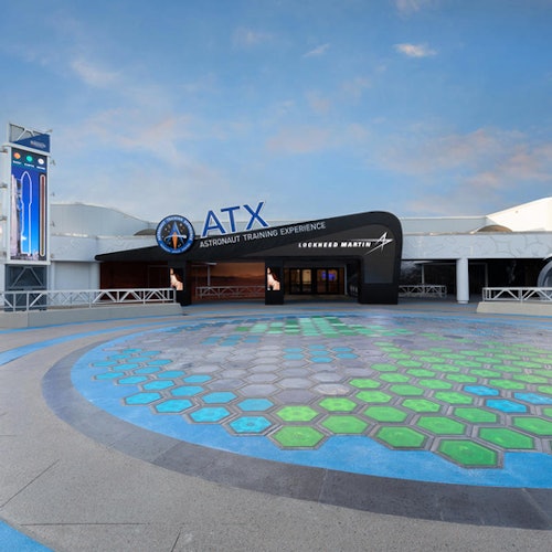 Entré till "Astronaututbildningsupplevelsen" av Lockheed Martin, med en geometrisk mönstrad gångbana och klarblå himmel.