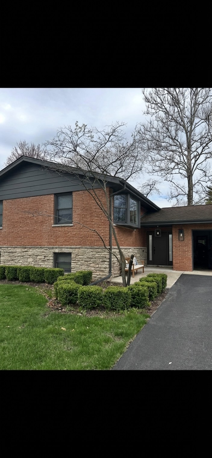Brick house exterior update — charcoal siding, dark trim, shutters removed, modern black door