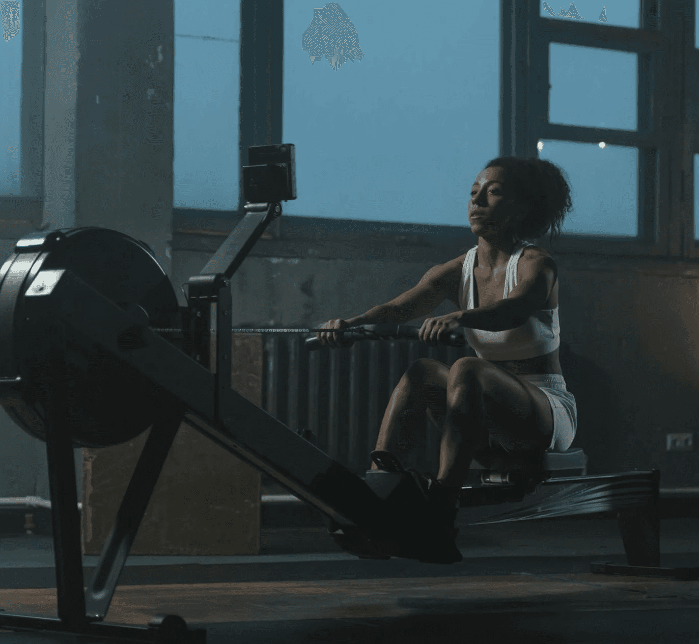 Woman stretching with arms overhead in a gym.