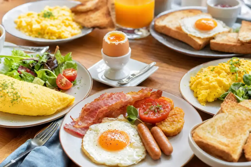 A lavish breakfast spread featuring various egg products like fried eggs, omelets, and soft-boiled eggs on toast.