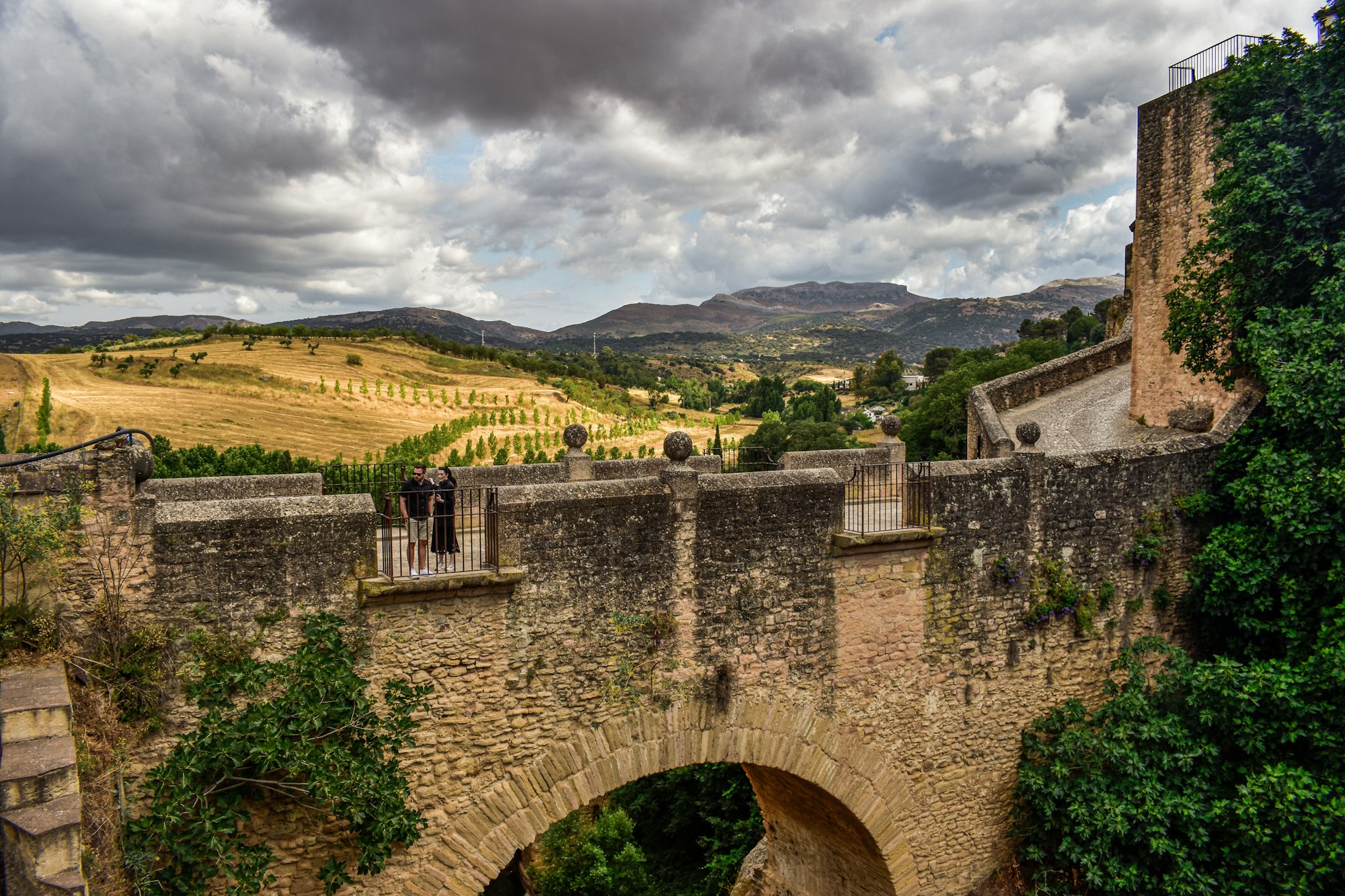 An old stone bridge over a river with hills behind