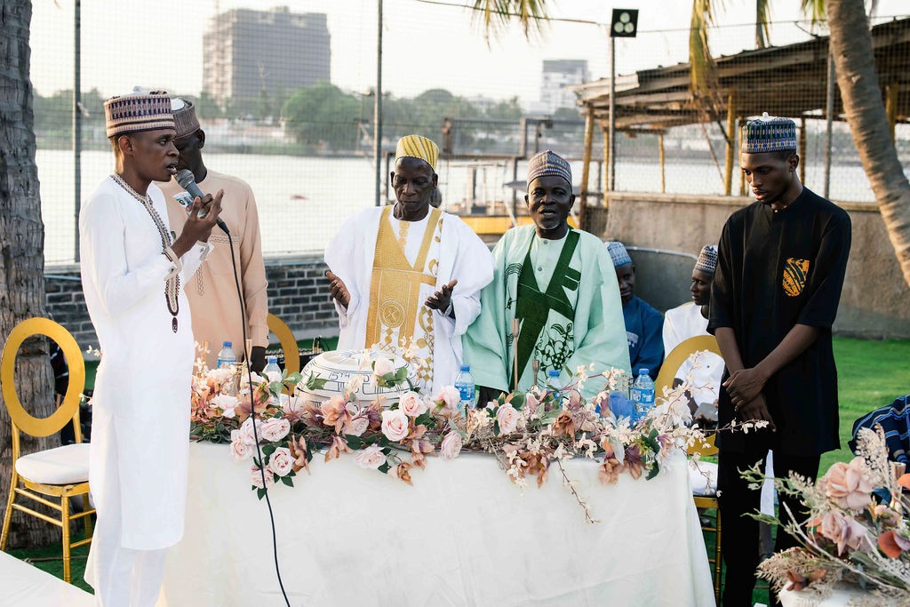 Luxury wedding planned by Victoria Brooks Events in Nigeria with elegant décor and beautiful reception. Groom in a blue suit and bride in a white wedding dress with flowers surrounded by family and friends.