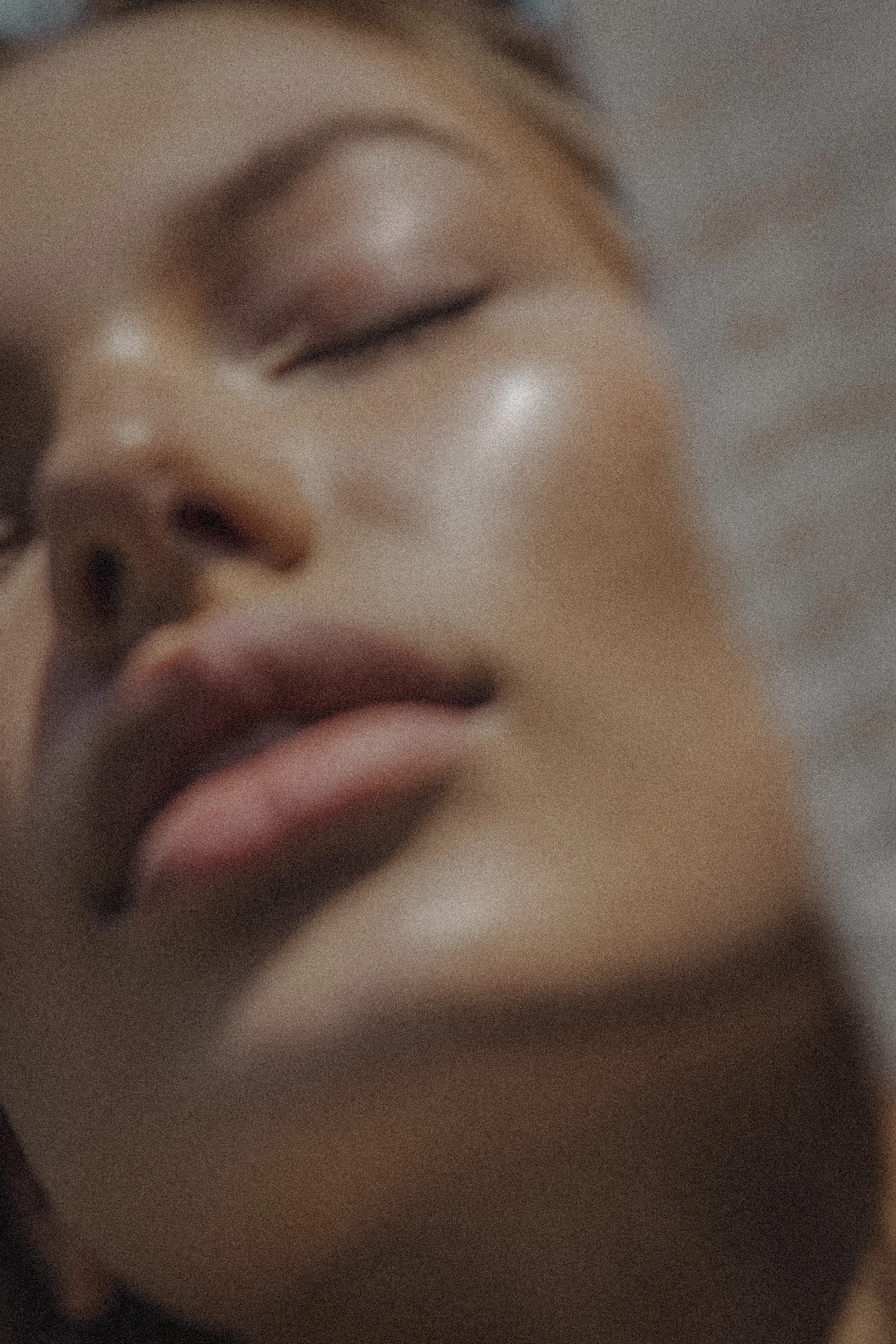 Woman lying with her eyes closed, lit softly from above