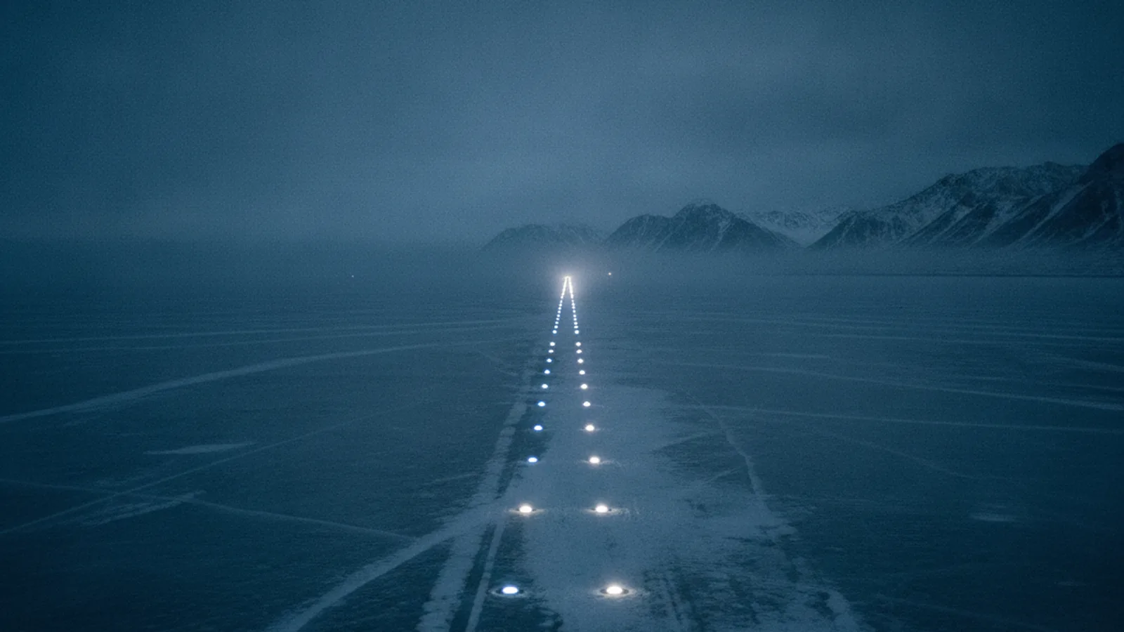Landebahnbefeuerung auf einem zugefrorenen See, die Lichter laufen auf einen Punkt am Horizont zu