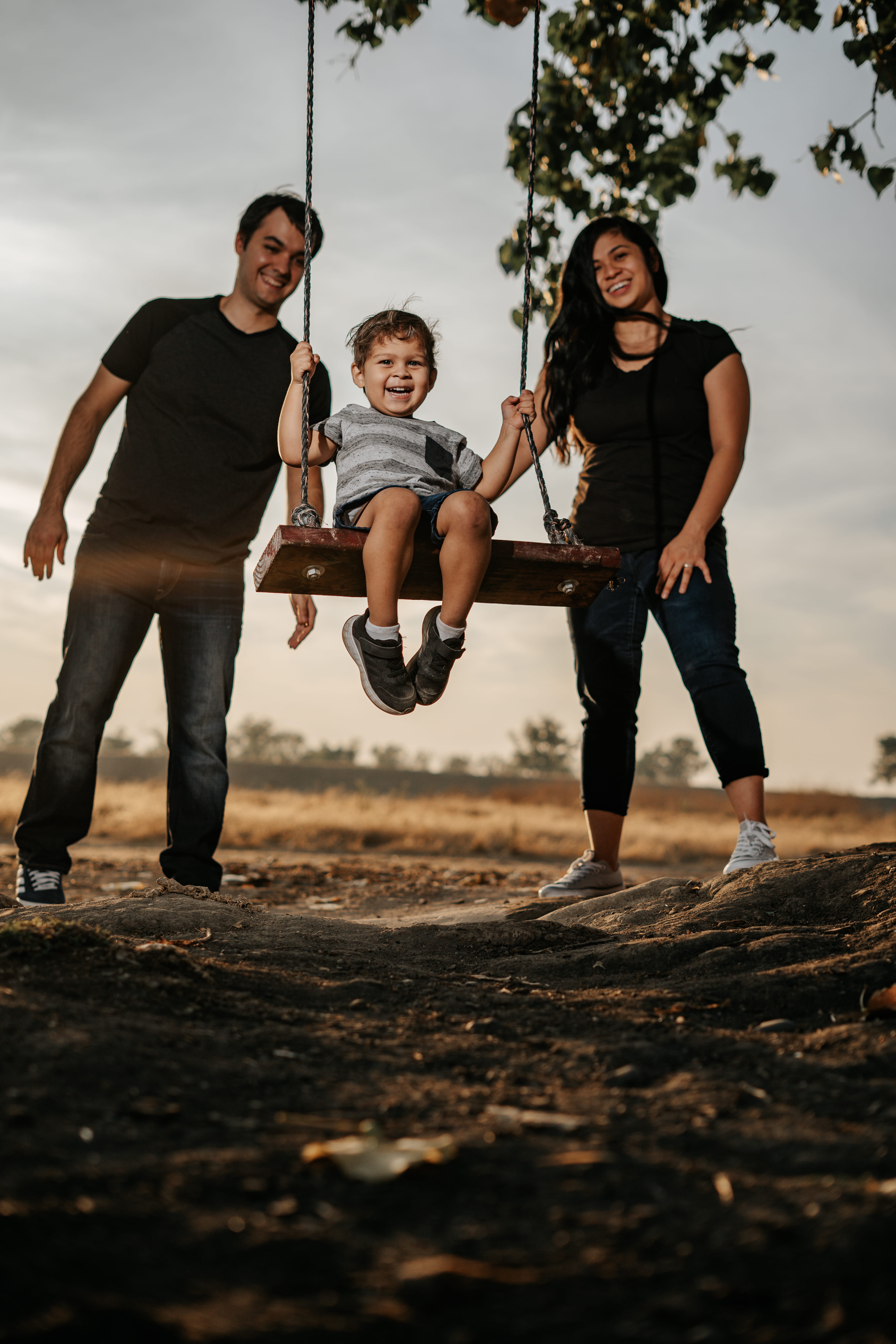 A couple in wedding attire walks hand in hand across a sunlit field.