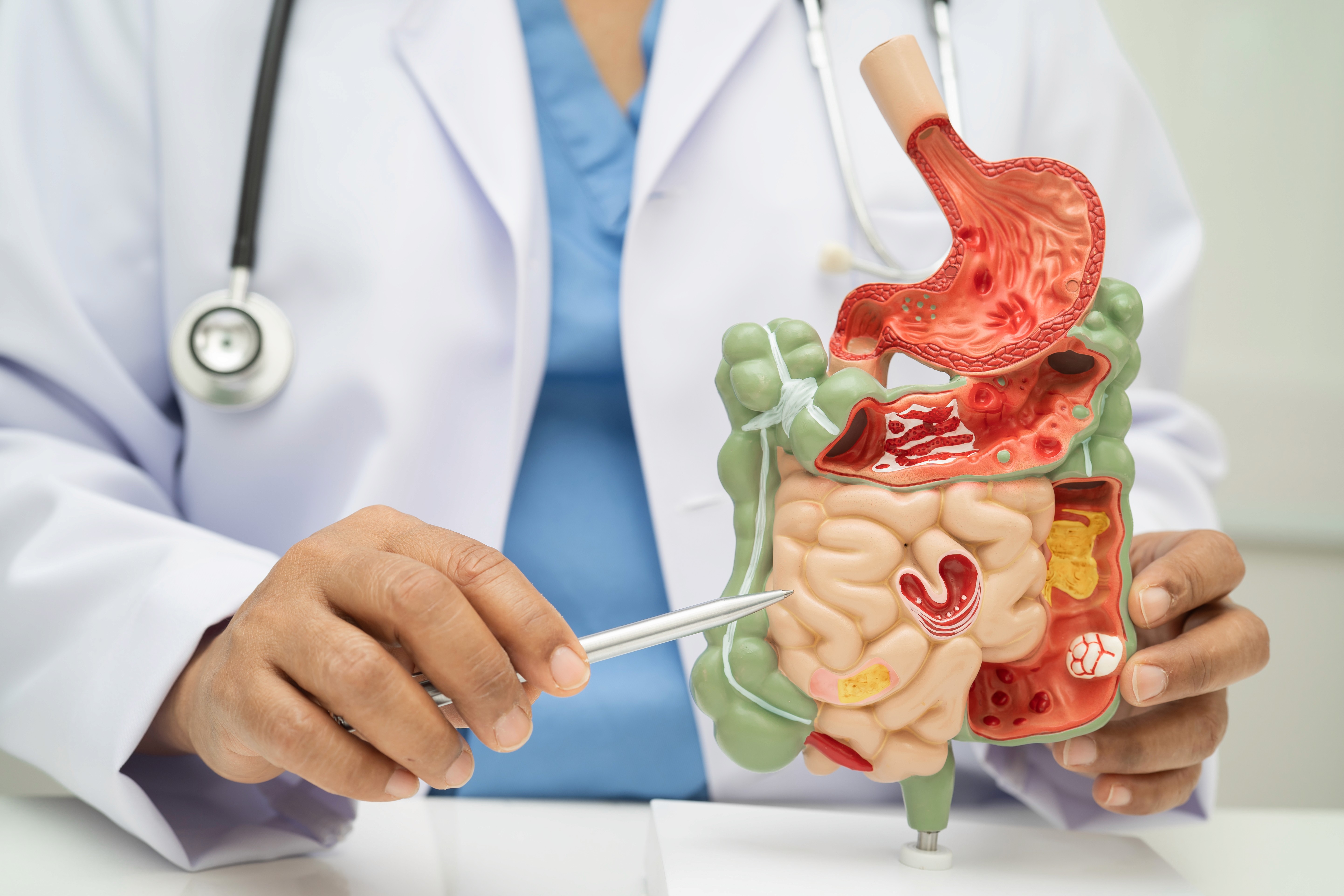 Group of people standing around a white desk during a casual meeting with laptops and coffee cups.