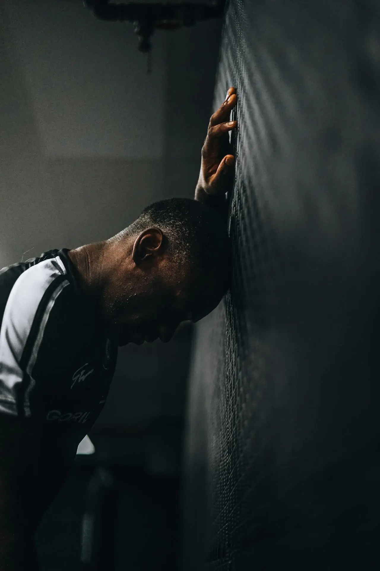a frustrated athlete leaning their head against the wall with their eyes closed