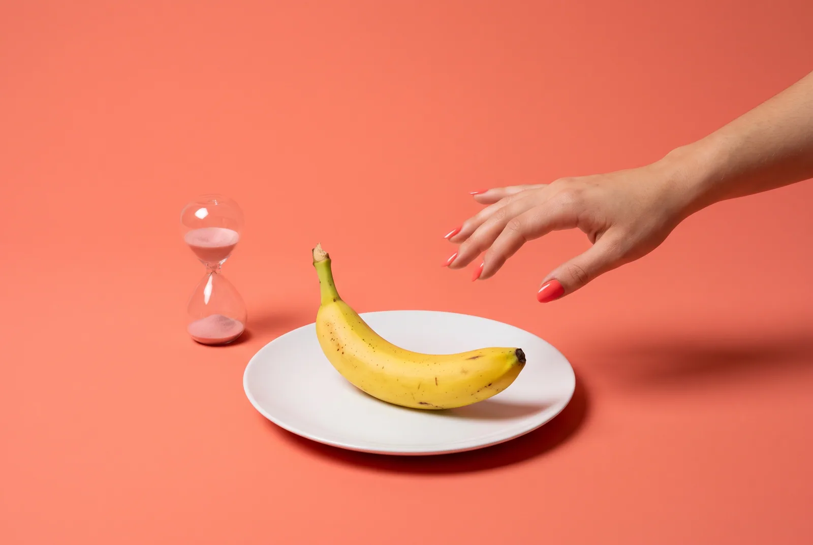 Alternative to accountability software concept: a cropped hand stopping mid-reach before a banana, next to a small hourglass