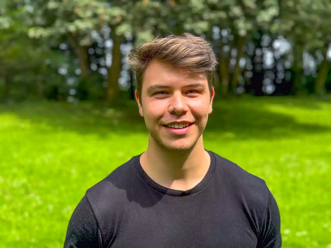 Portrait of Samuel Mitterrutzner, Co-Founder and CTO of CoachingArea, standing outdoors in a green setting. Samuel is a full-stack developer, second-time founder, former Italian Serie D football player and ex-tutor for Software Engineering at the University of Vienna.