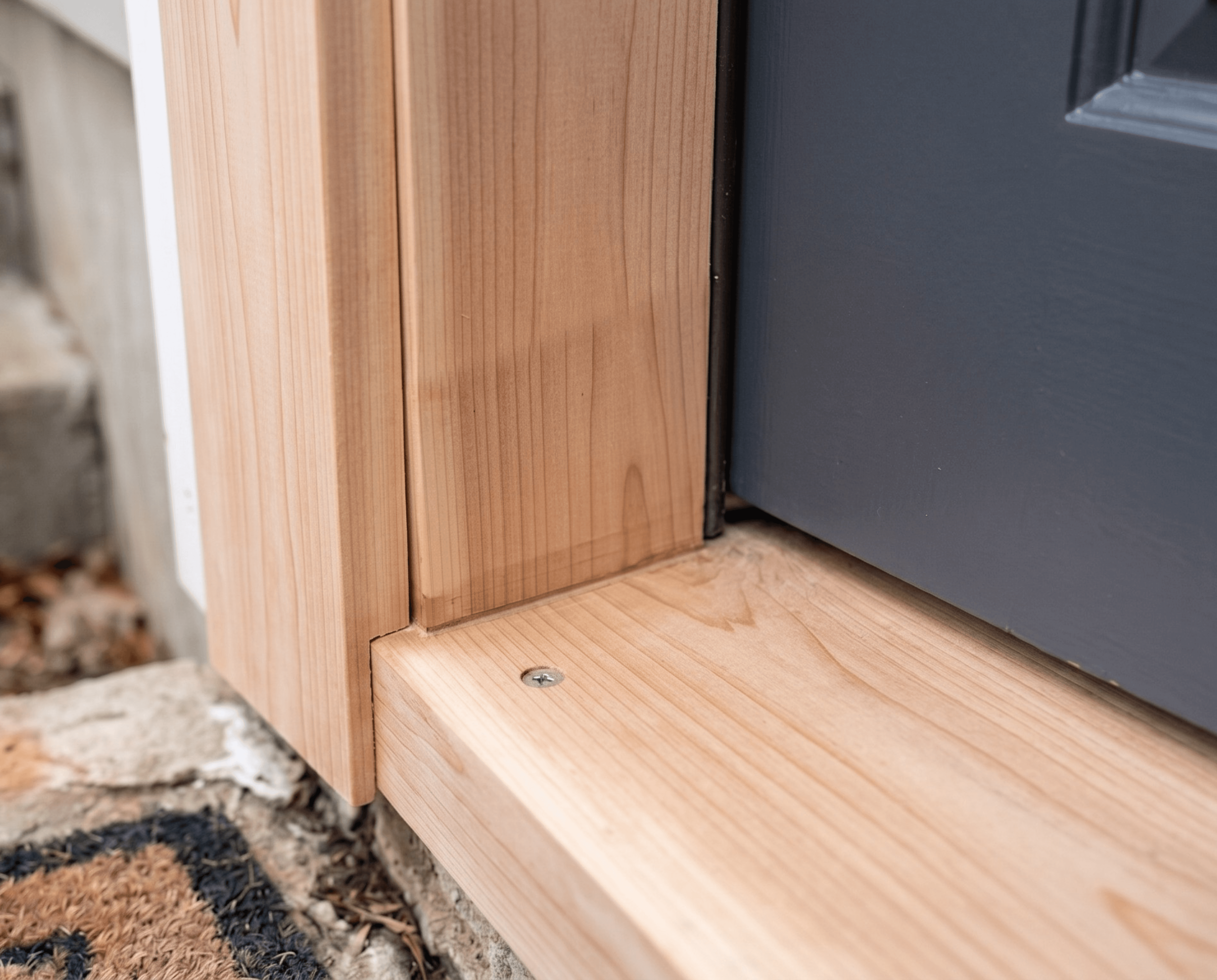 A completed exterior door rot repair showing a brand-new, custom-cut wooden threshold and door frame base, perfectly restoring the entryway's structural integrity