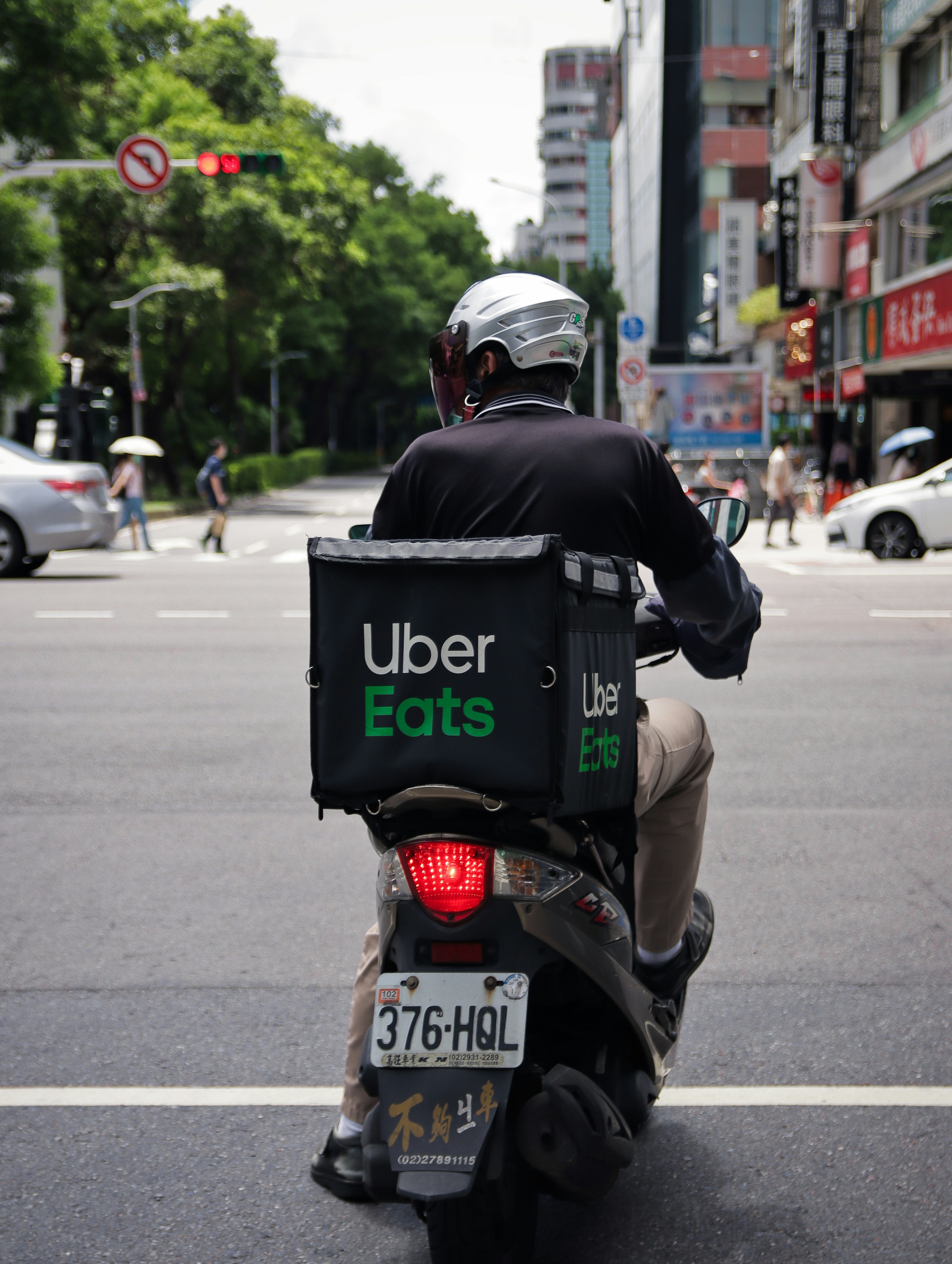 Uber Eats written on a box placed on a bike while the bike rider looks left.