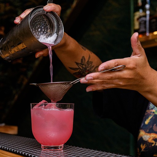 Mulher preparanado drink em um bar.