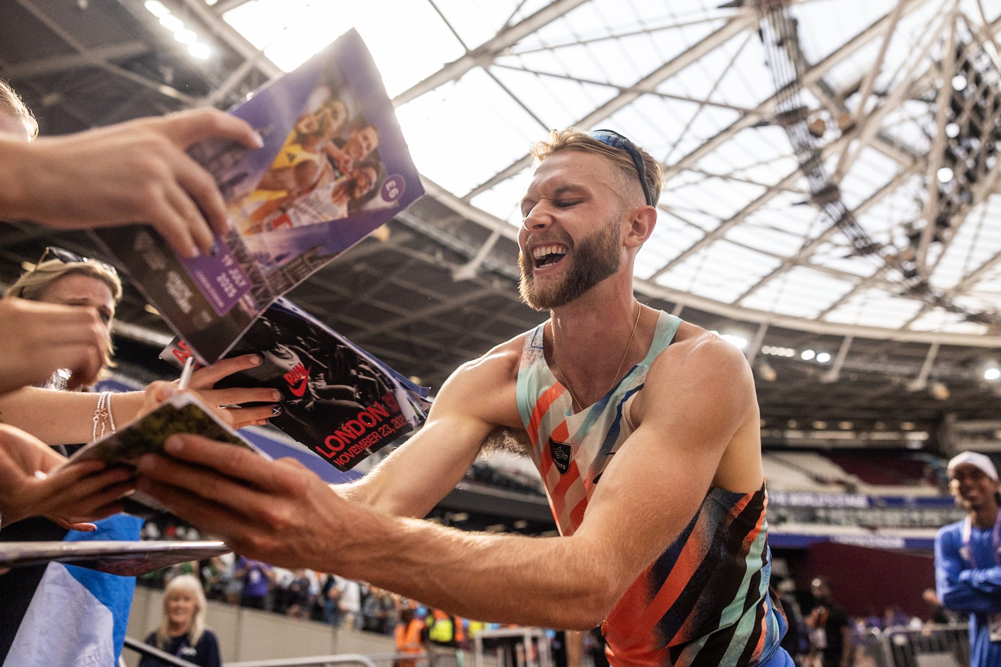 Three models standing in a wheat field, wearing beige suits.