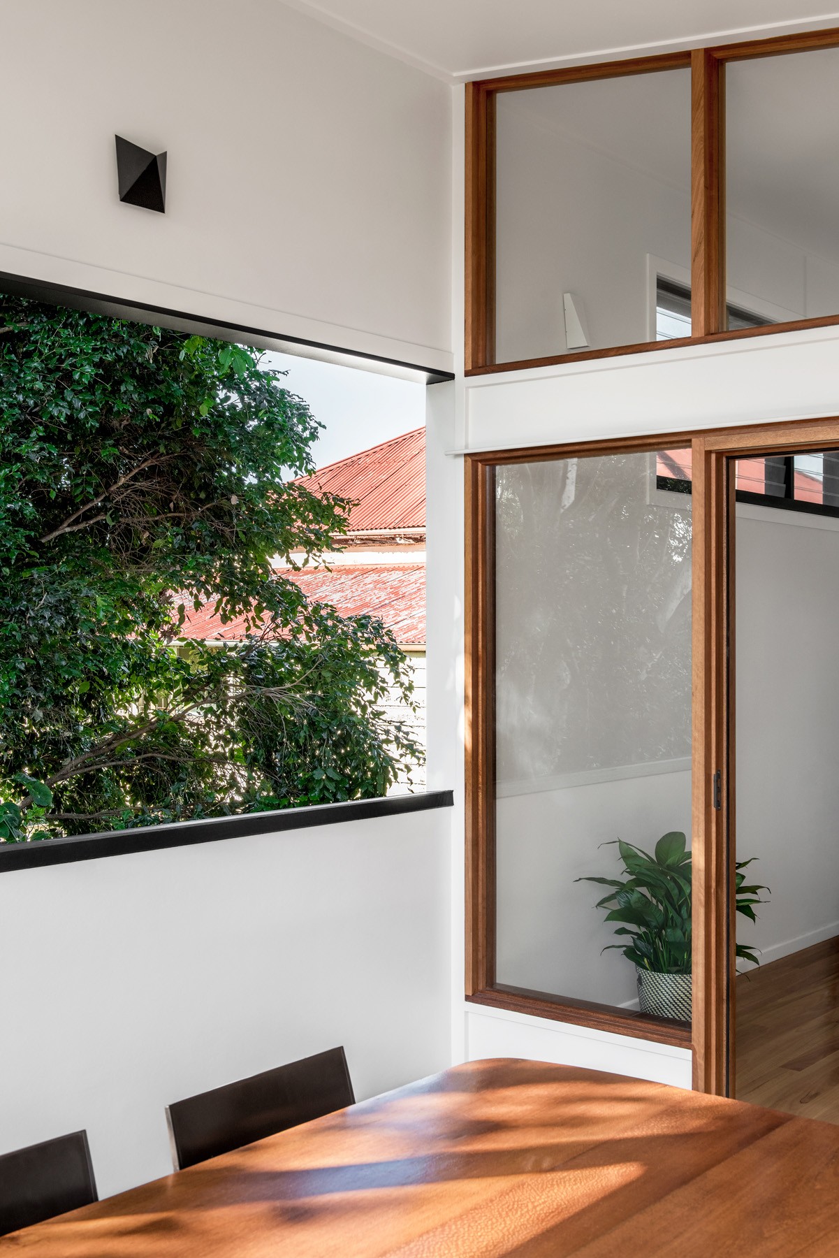 Deck-to-interior connection at Oxford Cottage, with timber-framed glazing opening the living spaces to the treed outlook beyond.