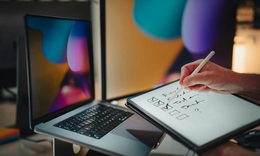 A person checking off a security compliance list on a tablet next to a laptop for video localization workflow