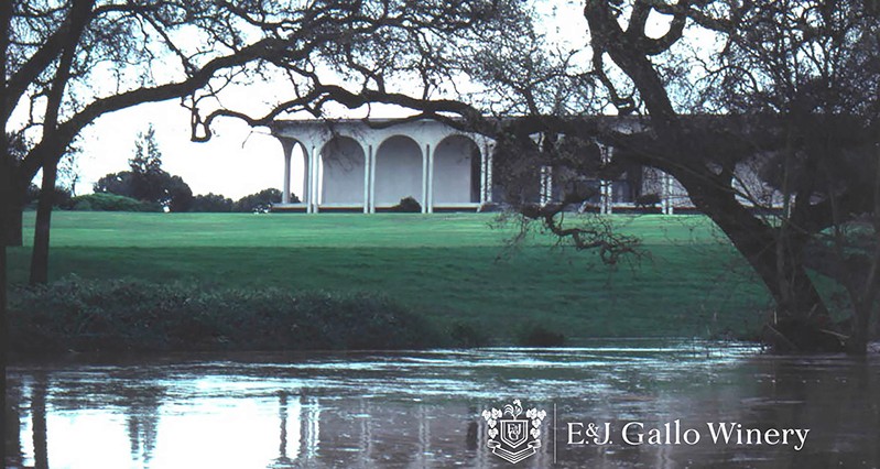 A photo of a white house, green grass, and some trees near a lake. The text on the photo says: E&J Gallo Winery.