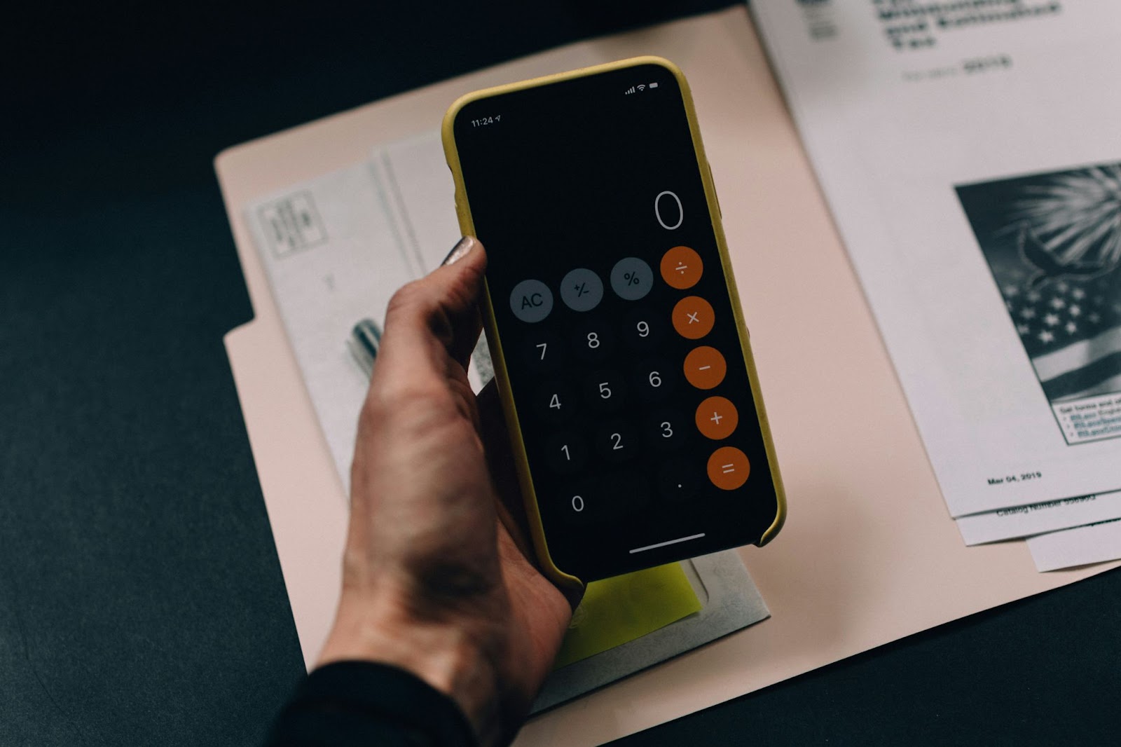 Someone holding a phone above a stack of bills