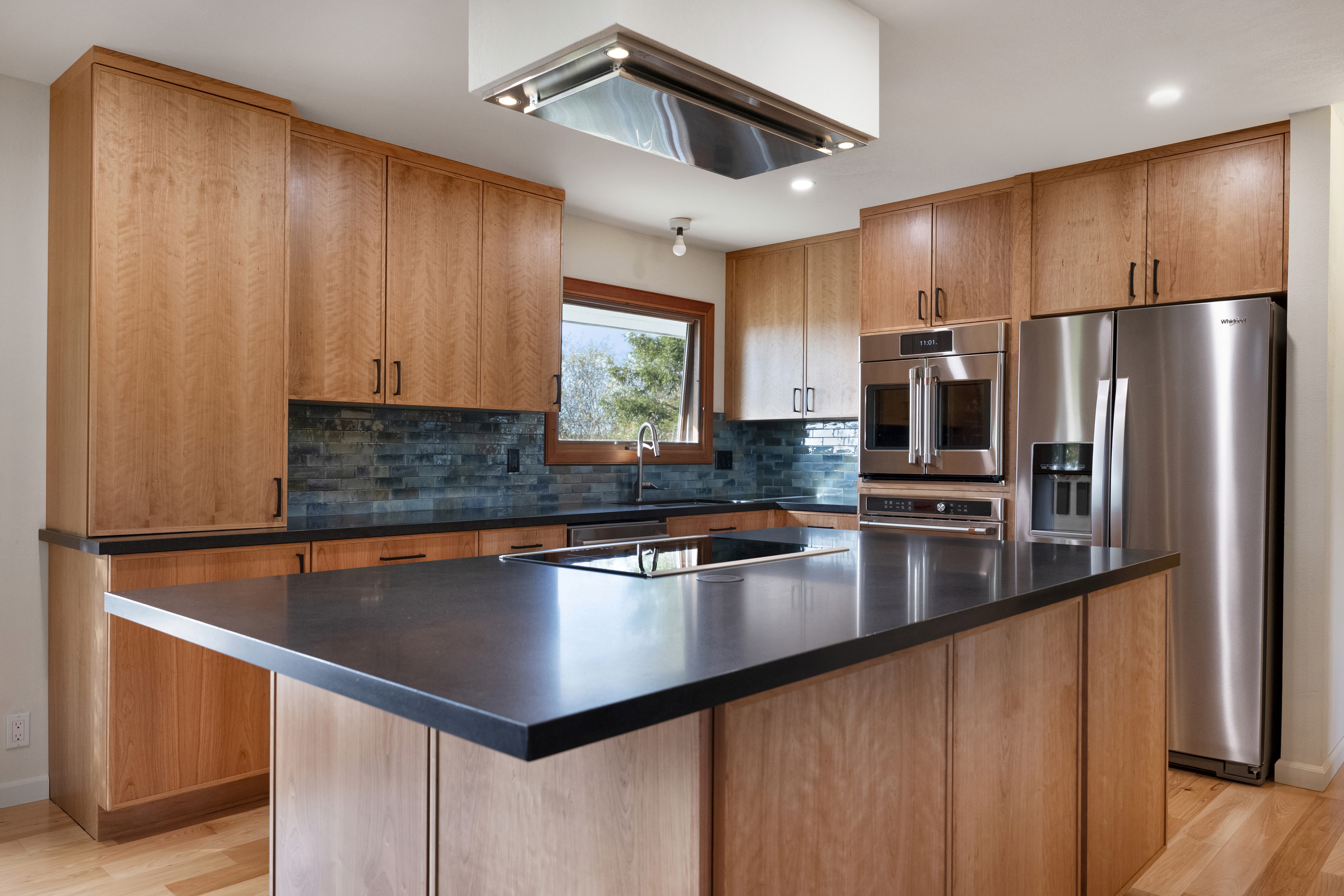 “Bright modern kitchen with light wood cabinets, large island, and wood ceiling with skylights”