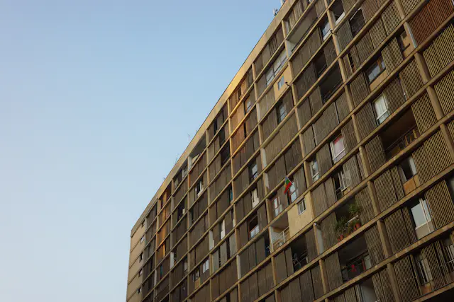 A tall apartment building with many windows against the sky
