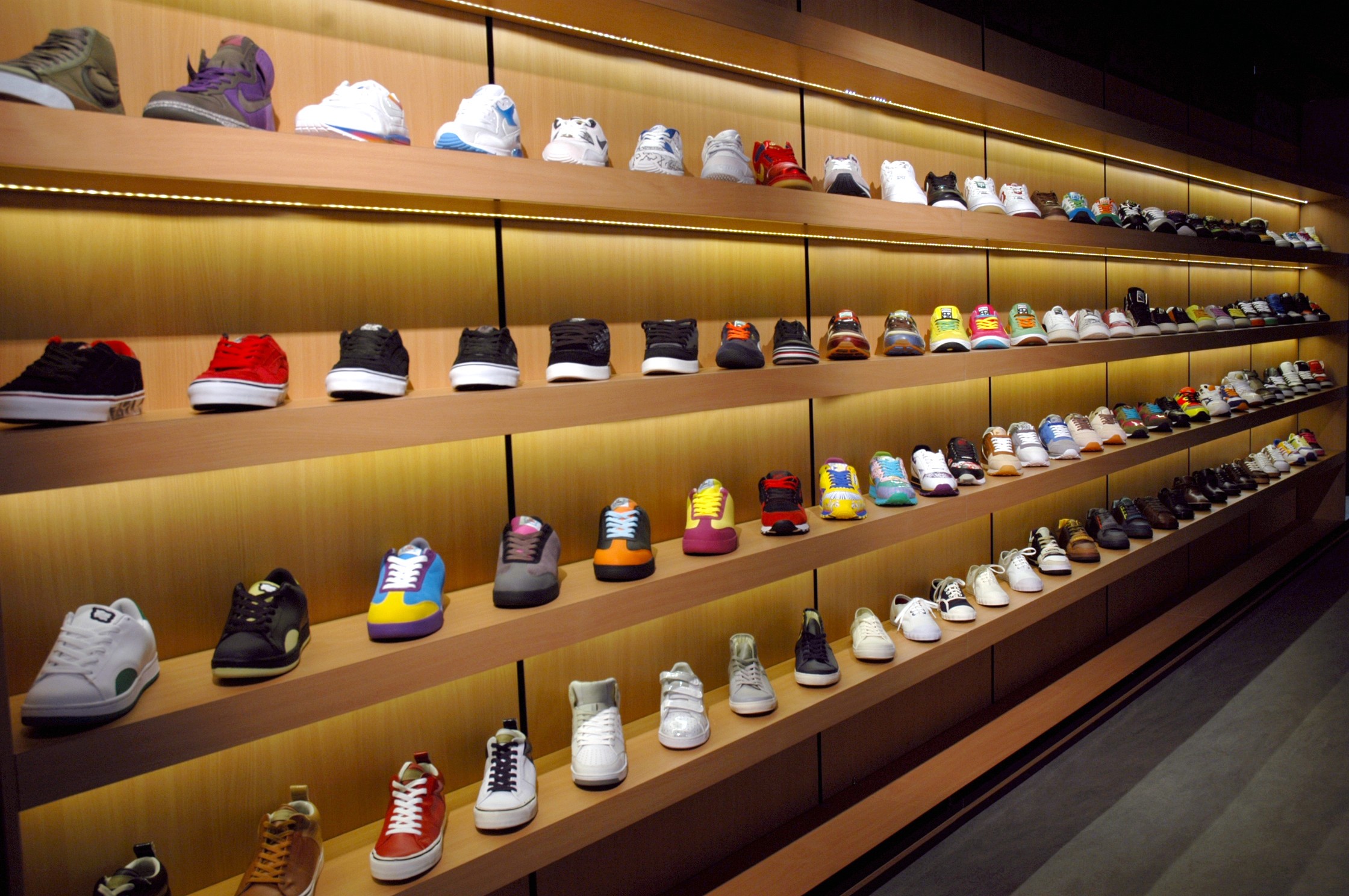 Full-length sneaker wall display with integrated timber shelving and warm recessed lighting, Apartment Store Brisbane.