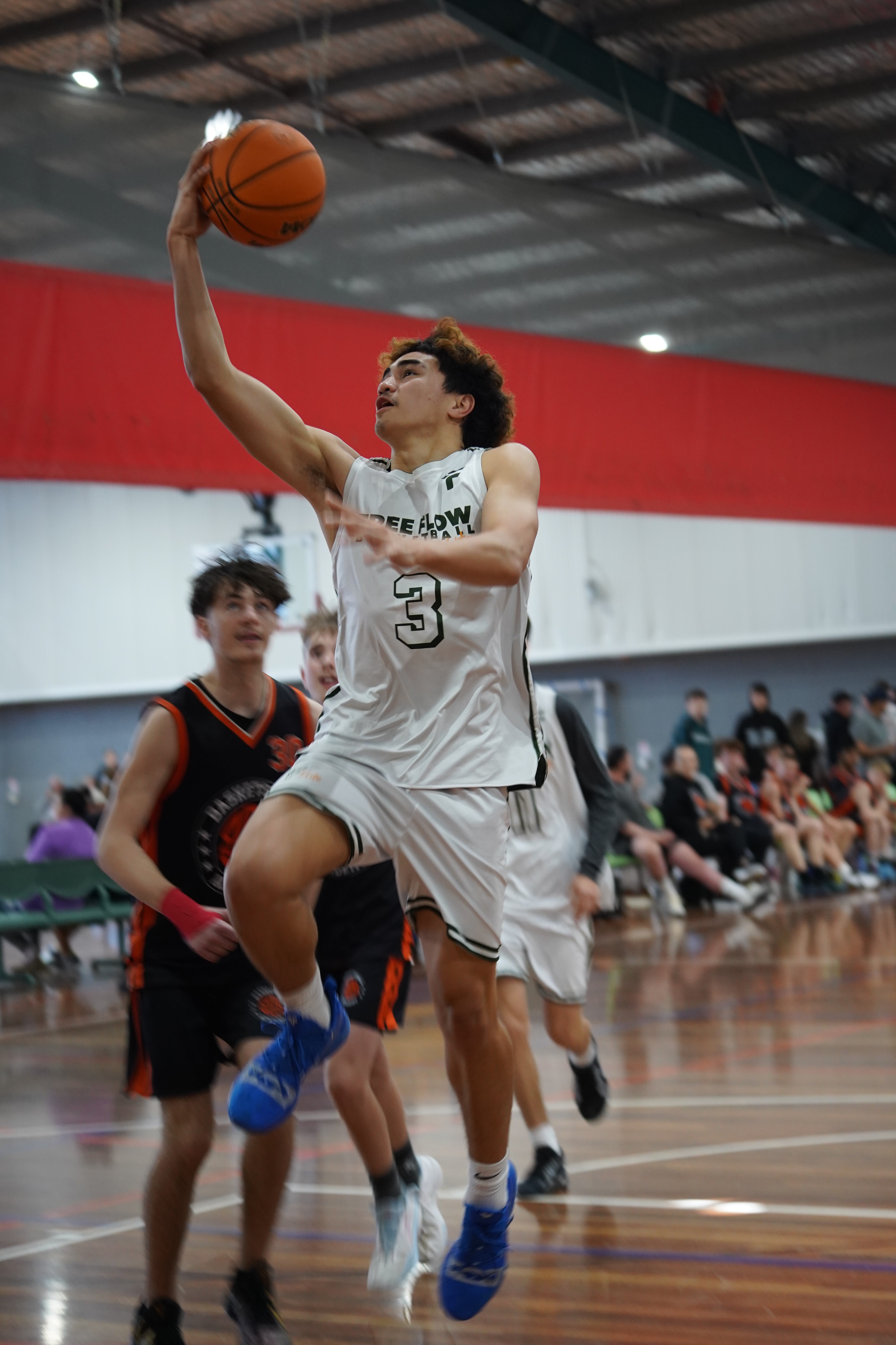 Free Flow Basketball player mid dunkj as the opposing teams player watches in shock