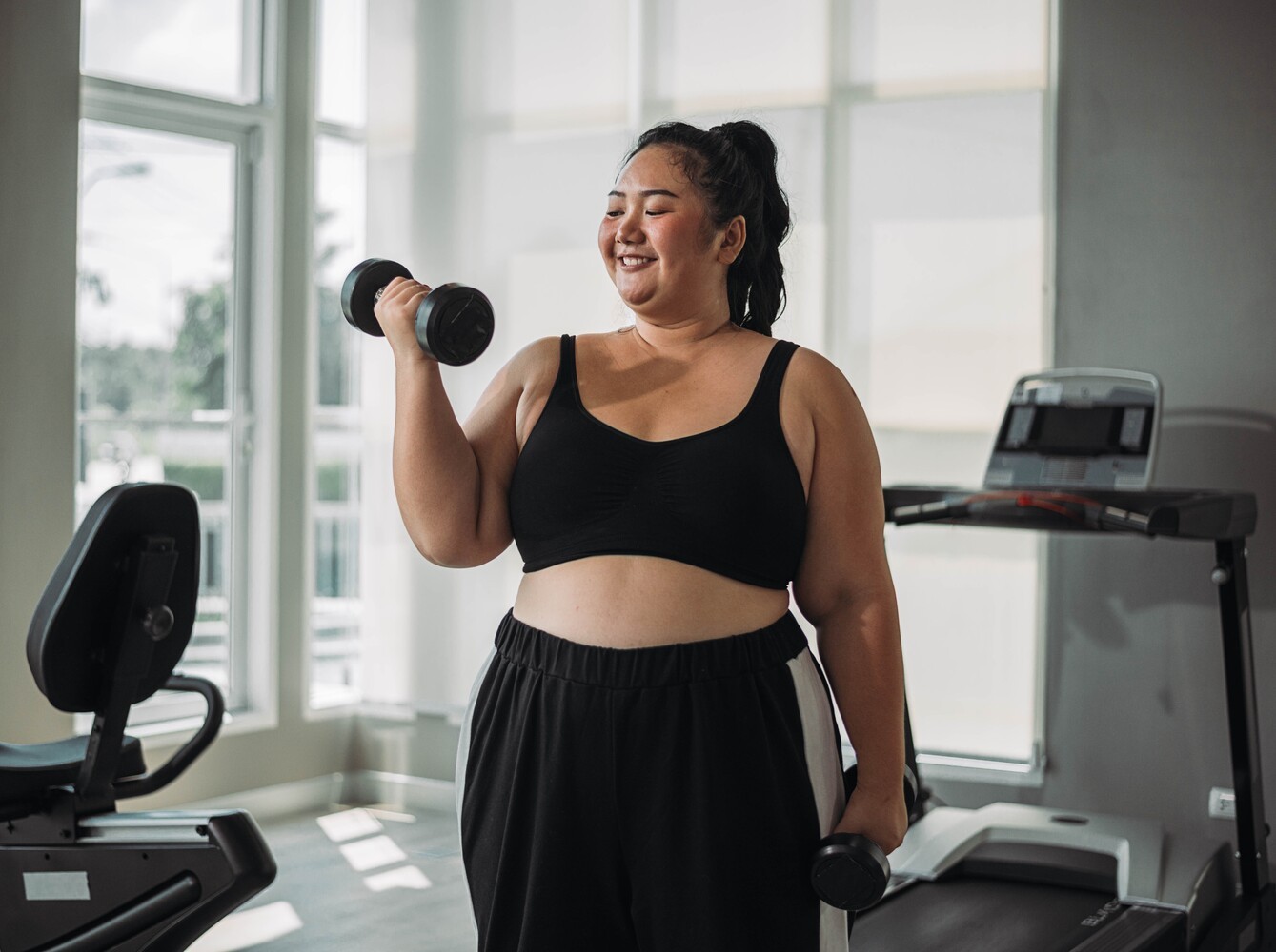 woman doing light strength training with dumbbells in her home gym during her weight loss exercise program