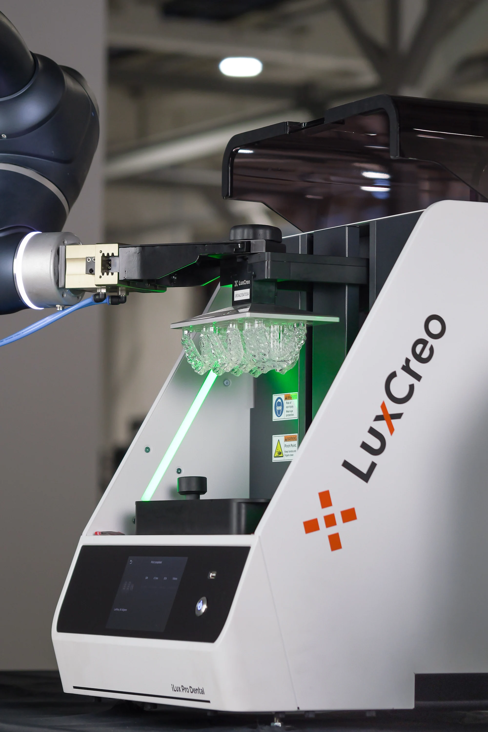 Robot arm harvesting a build platform with fresh 3D printed aligners from the LuxCreo iLux Pro Dental printer.
