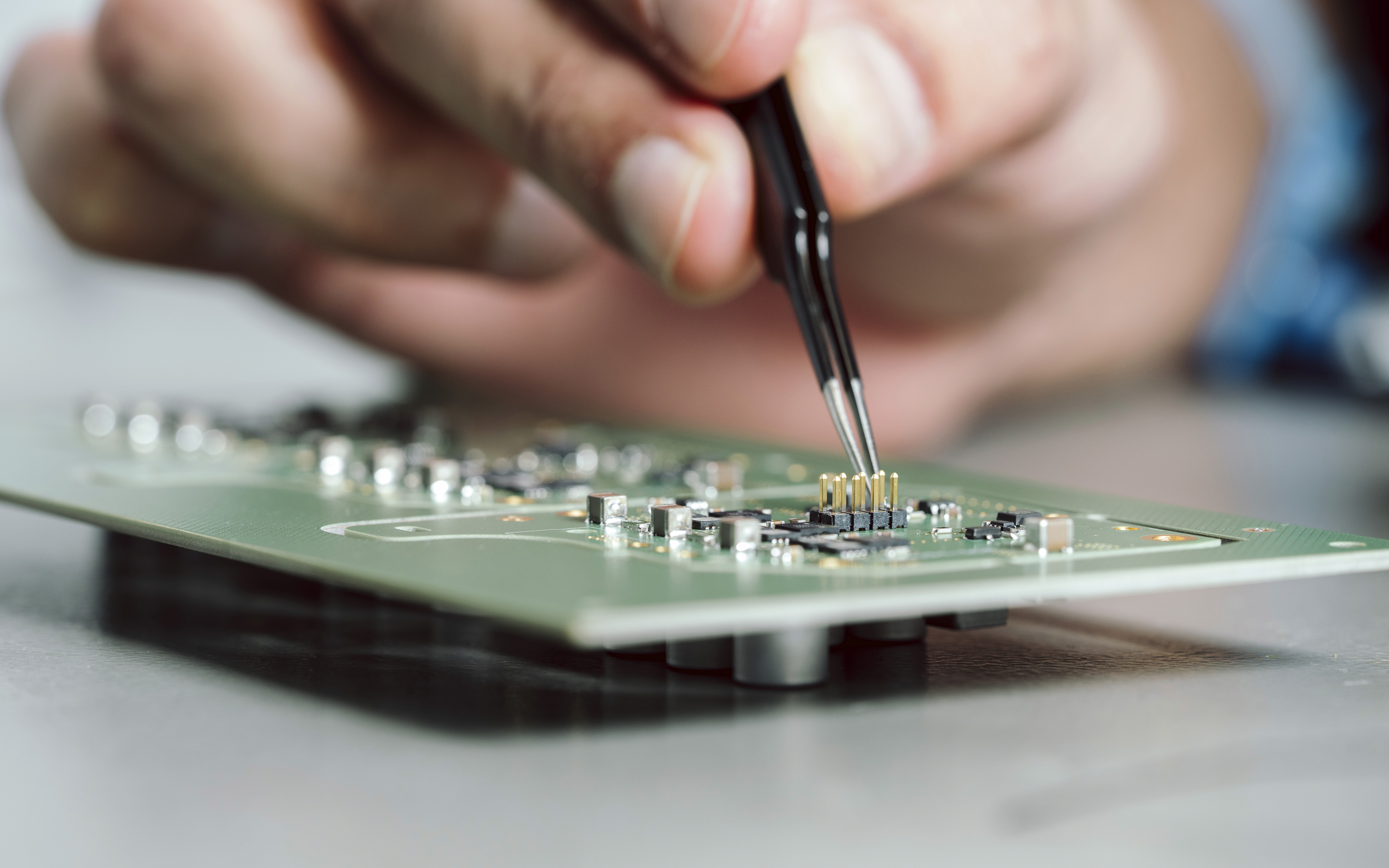 A close-up of a hand using a pen to mark or annotate a printed circuit board.