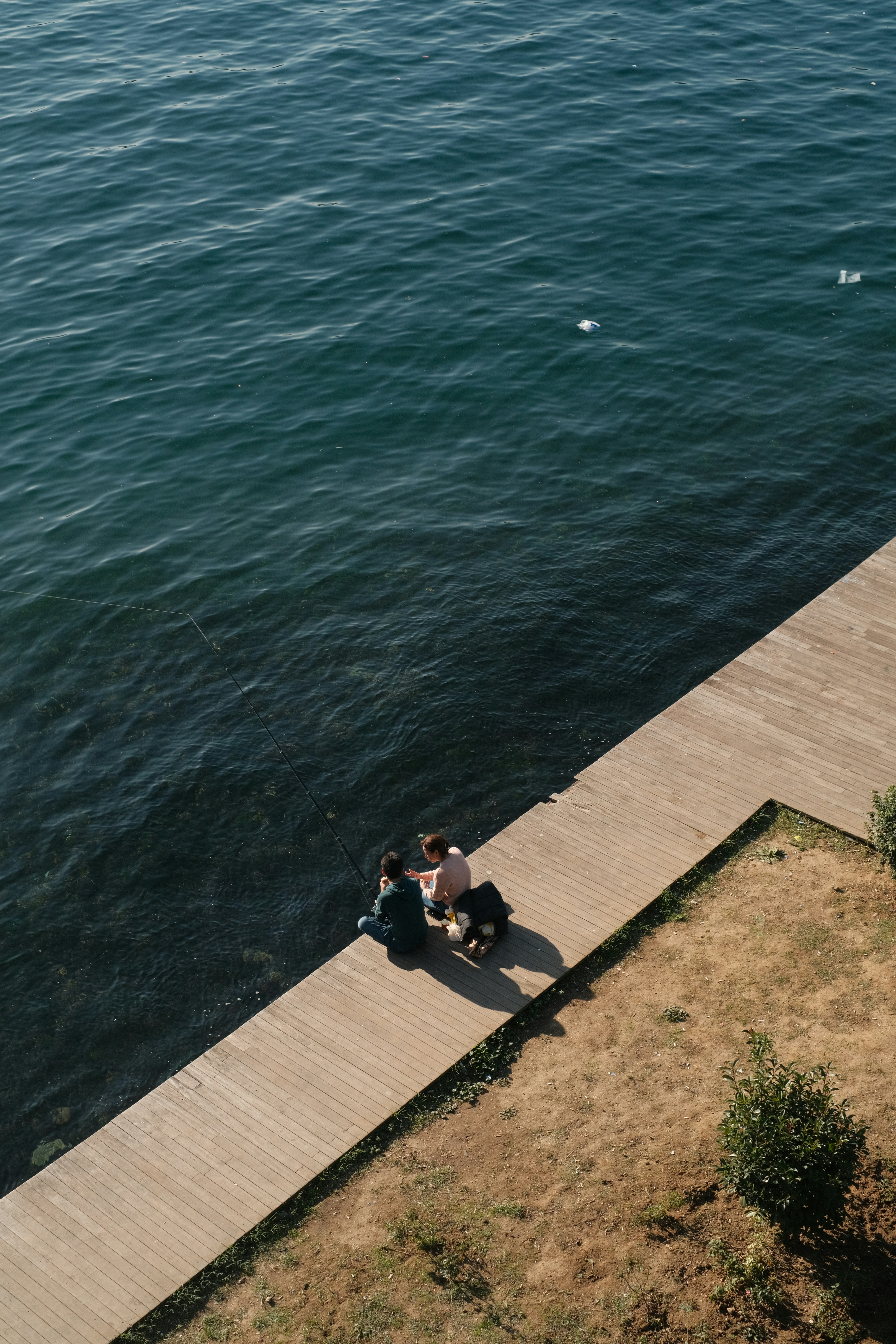 a group of people sitting on a dock by the water