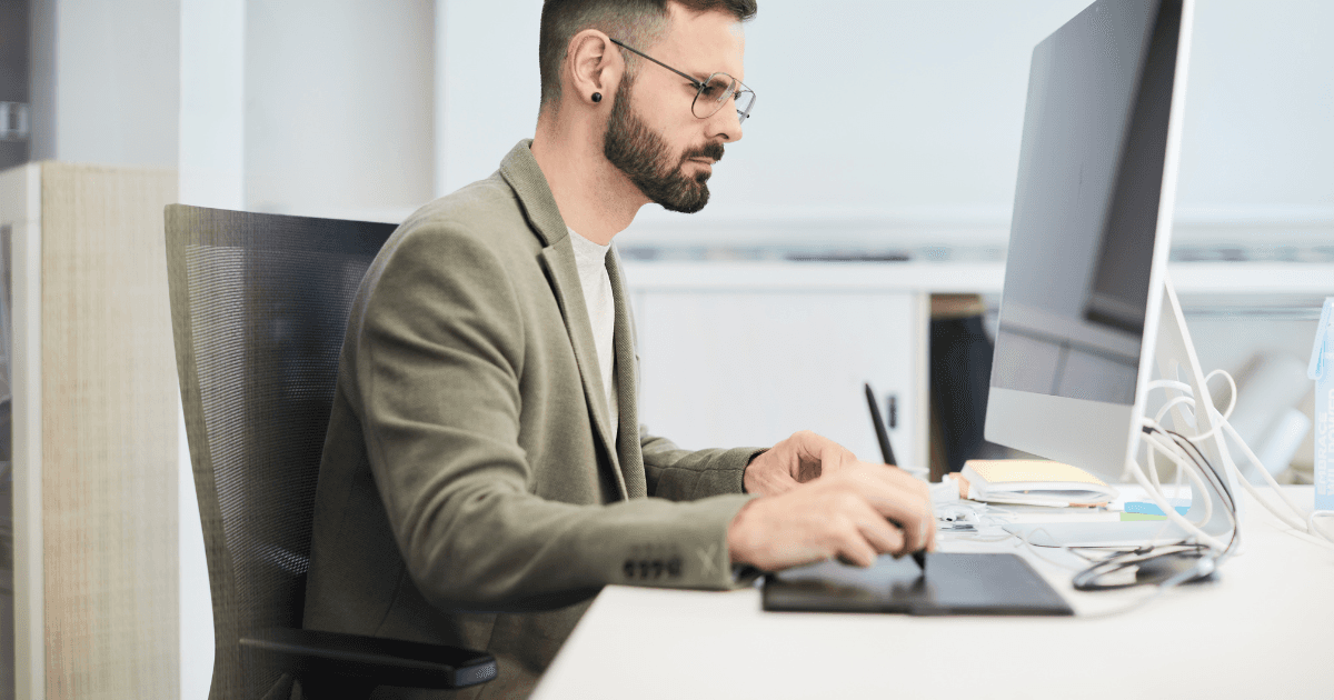 A person at a work desk with a laptop, U.S. flag in the background