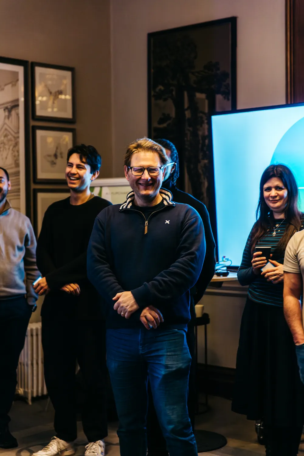 People standing and smiling in front of a screen.