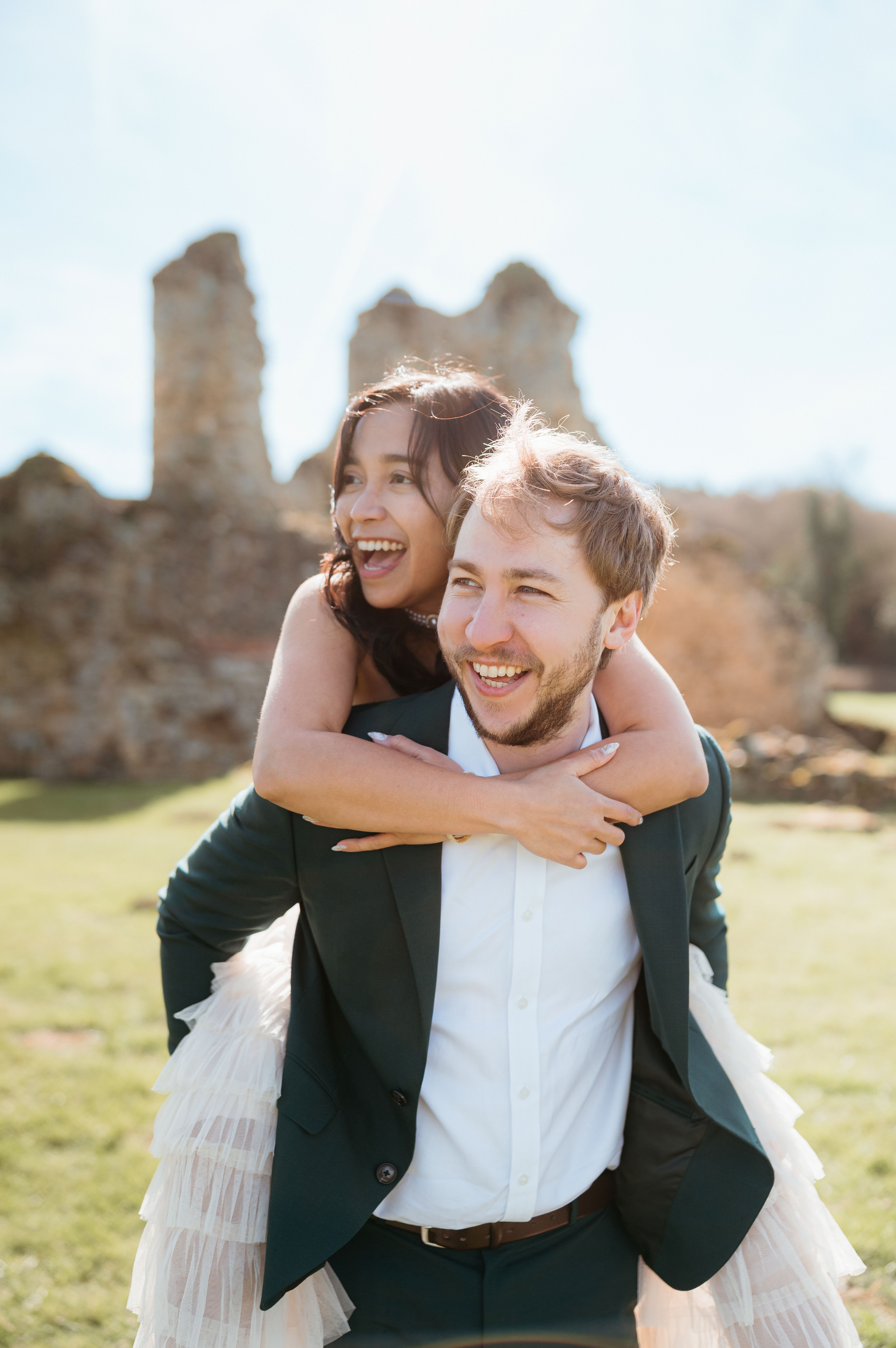 A bride and groom share a kiss, enveloped in the bride's flowing veil. The soft focus and gentle light convey a romantic, intimate atmosphere.