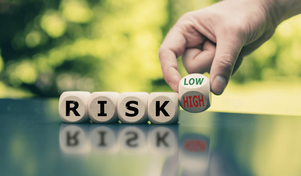 A smiling man with curly hair is sitting at a desk, looking at the camera, with a laptop and a lamp in the background.