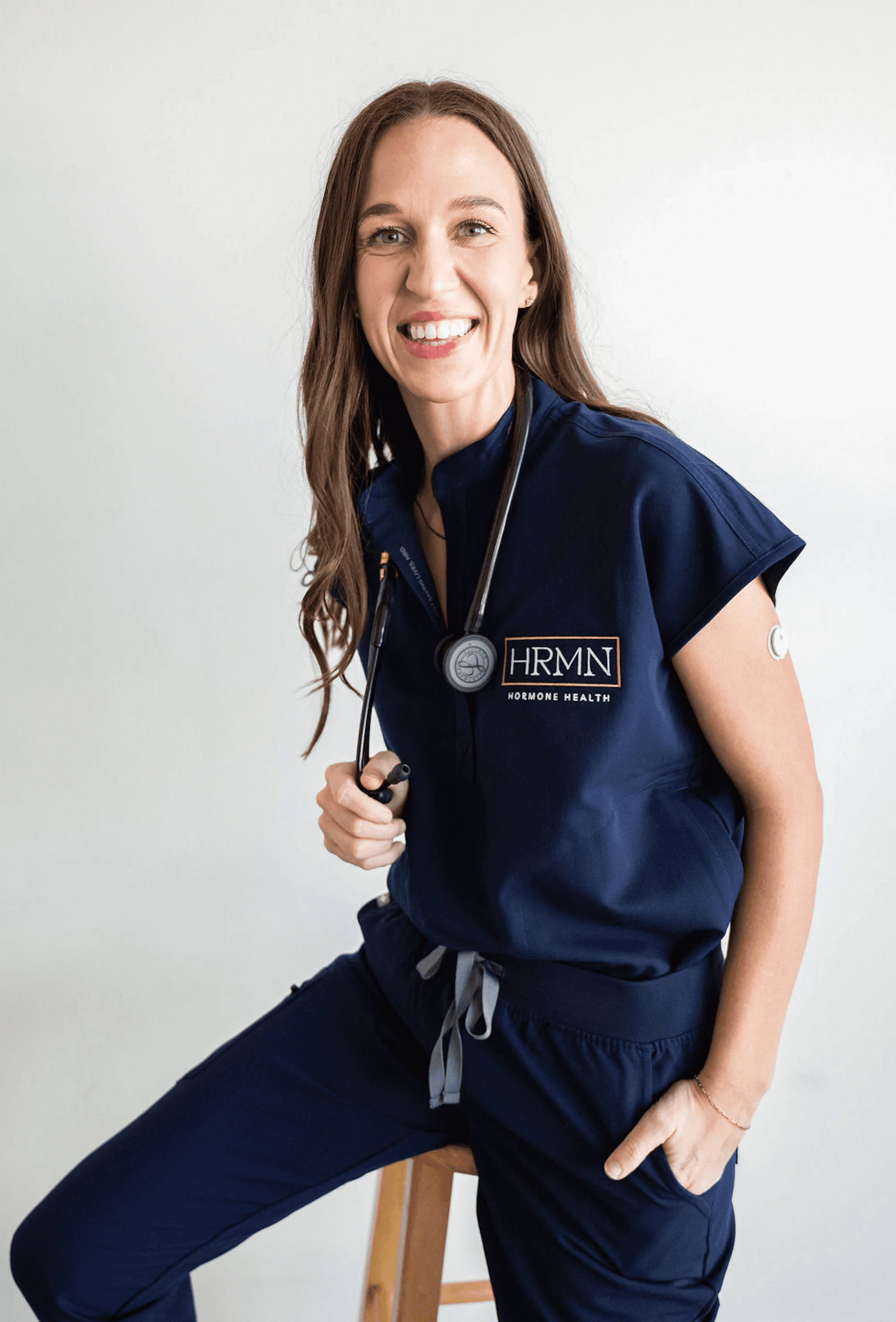 Portrait of Chelsey Galipeau, a certified Physician Associate, smiling in a medical office with neatly arranged health products and supplements on display behind her.