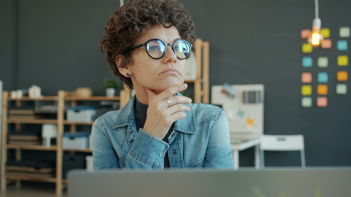 A woman thoughtfully comparing online dietitian platform options at her desk
